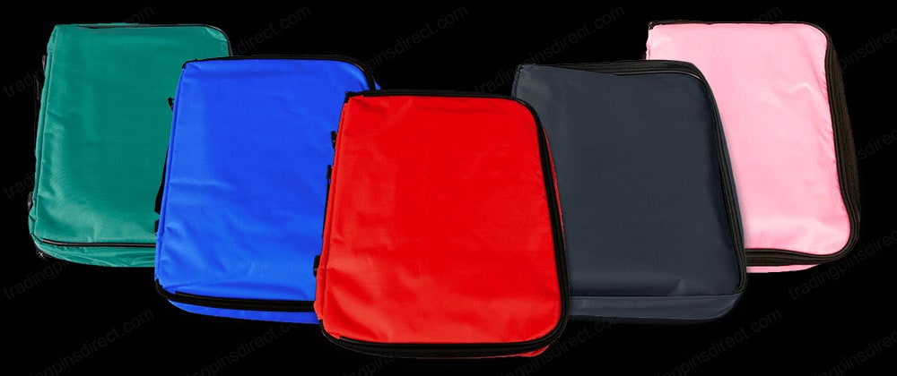 Five zippered pouches arranged in a row, featuring bold colors: green, blue, red, black, and pink. Each pouch is designed for storing and organizing items such as trading pins, showcasing their sleek and simple design.